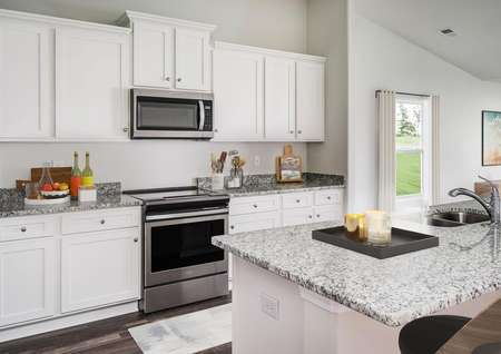 Staged kitchen with granite countertops and white cabinets.