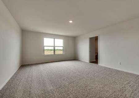 The spacious master suite has bright windows, white walls and brown carpet.