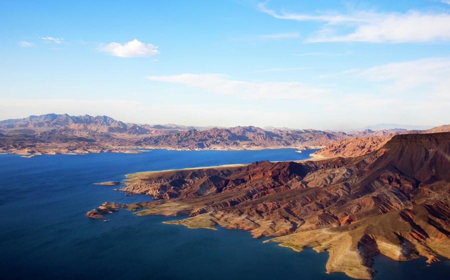 Nevada Lake Mead with dark blue waters, rock-covered banks, and lightblue skies with white clouds