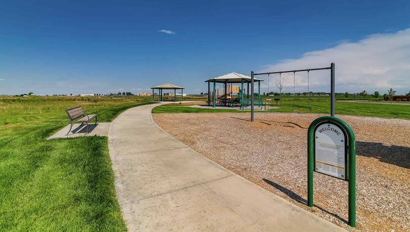 Community playground area with multiple gazebos and long sidewalk through it.