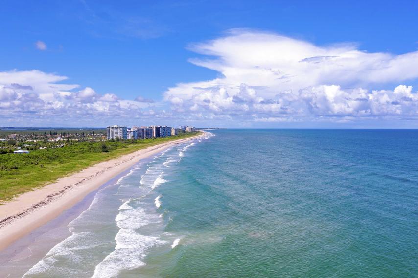 Fort Pierce, Florida beach with waves crashing in, white sand as far as the eye can see, and condo buildings in the distance