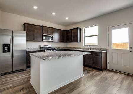 The stunning kitchen has stainless steel appliances, brown cabinetry and granite countertops with a large island.