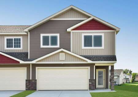 Exterior photo of the Blackberry townhome by LGI Homes with taupe and beige siding and red shake shingles, water table stone and a glass front door.