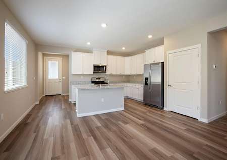 The kitchen is open to the living room and has white cabinets, granite countertops and wood style flooring.
