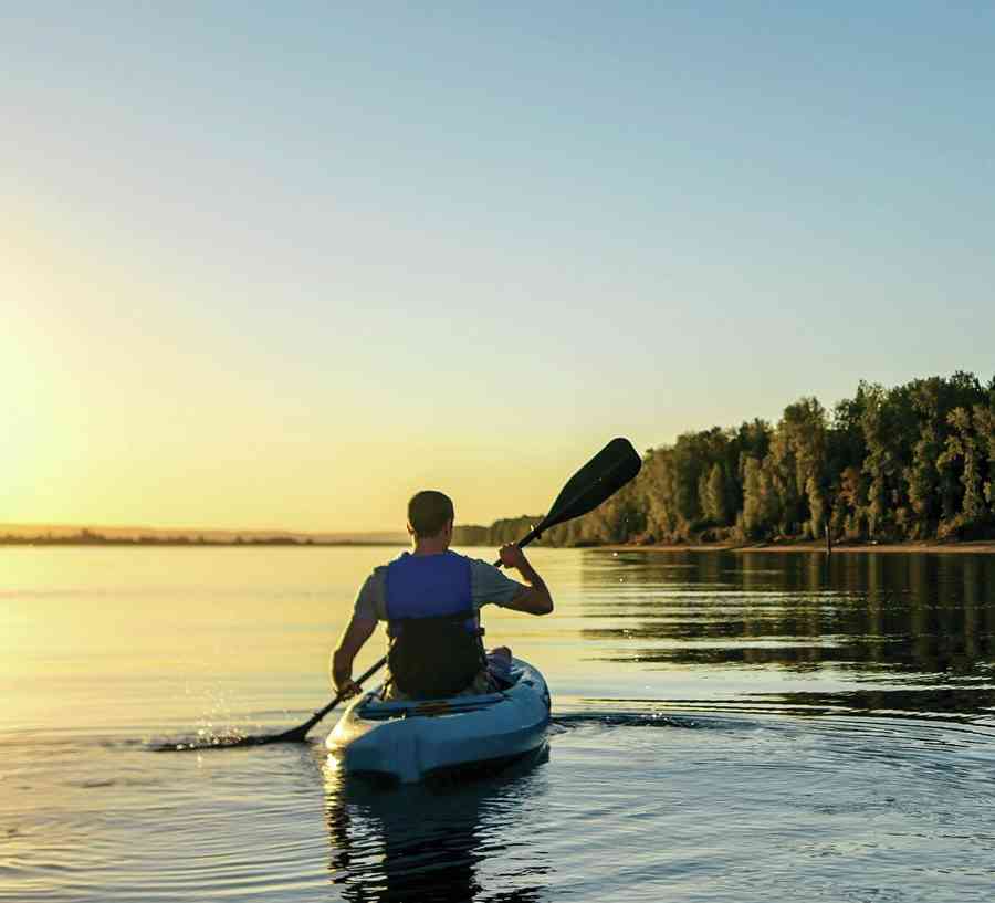 Man in kayak on river at sunset.