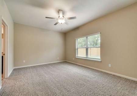 Tahoe bedroom with ceiling fan, off white walls and brown carpets