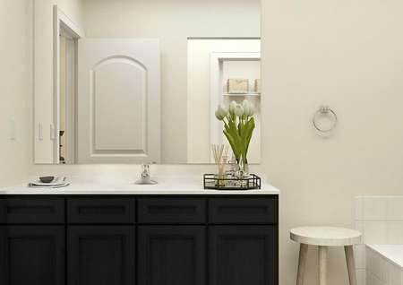 Rendering of the Maple master bath focused on the vanity with dark brown cabinets and decorated with a tray holding flowers and a scent diffuser.