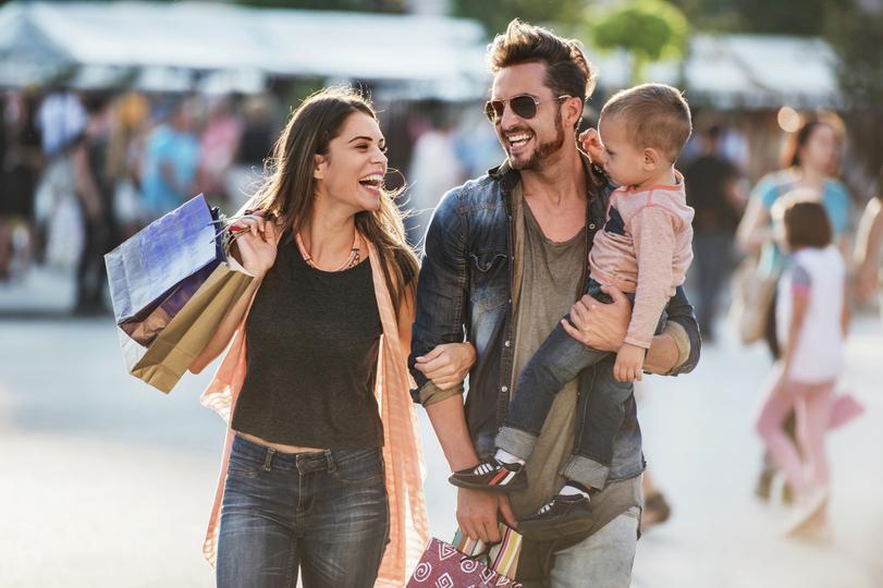 Young happy parents having fun while shopping with their son. 