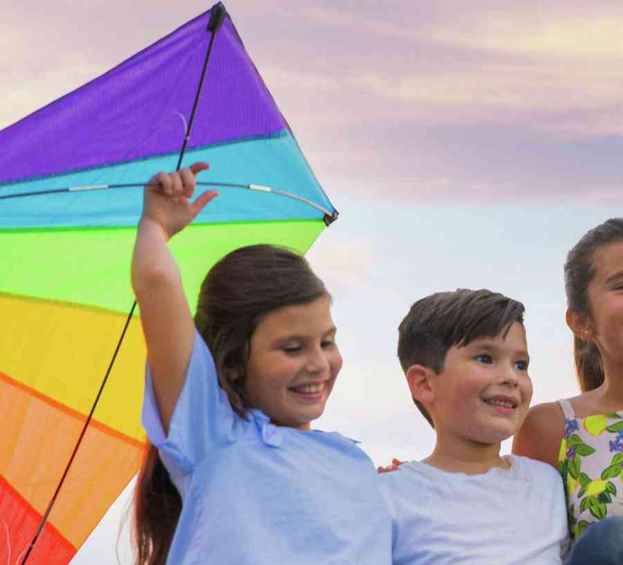 Kids in the park with a kite at sunset.