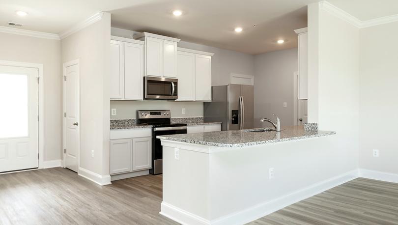 Kitchen with white cabinets, gray granite countertops, stainless appliances, recessed lighting and plank flooring.