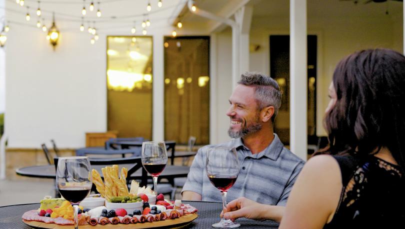 Couple drinking wine and eating a cheese board.