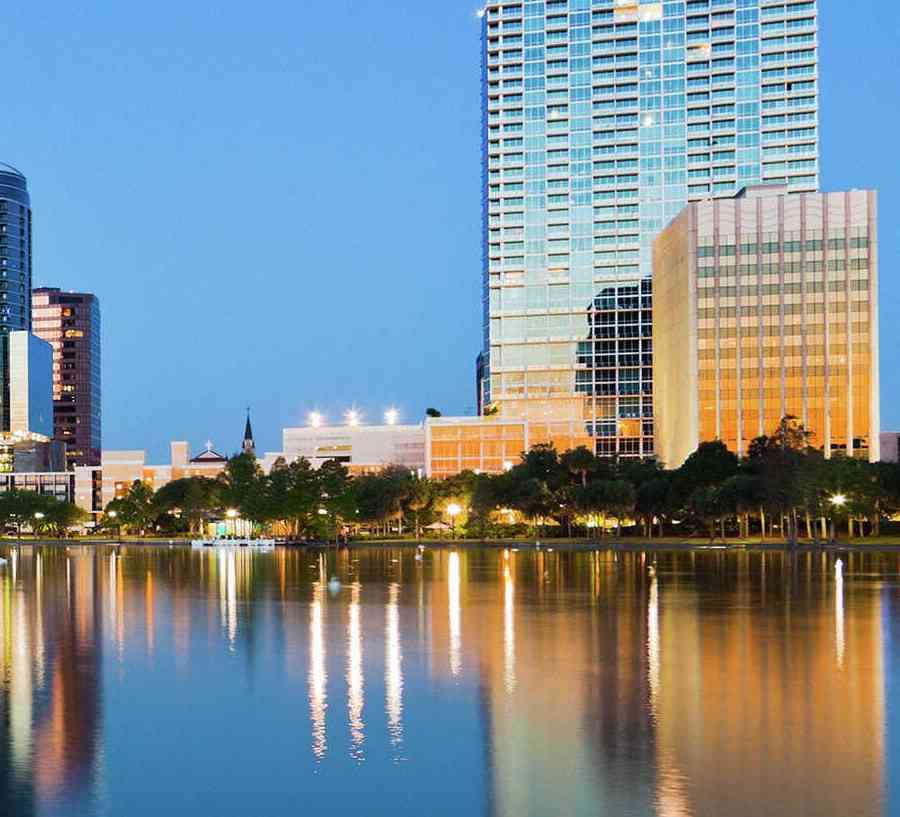 Orlando, Florida skyline at sunrise from Lake Eola showing calm waters and large office buildings reflecting in the water