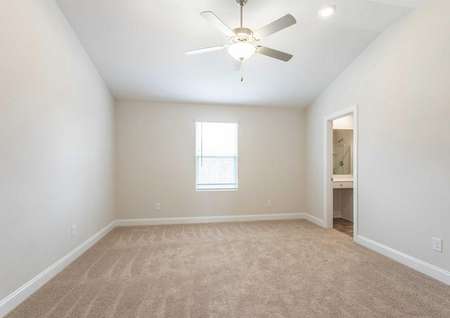 Avery master bed with vaulted ceilings, fan, and brown carpets