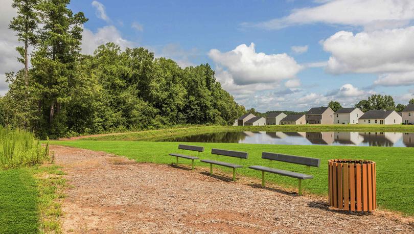 Dirt walking trail in the Autumn Lakes community that passes trash can and three benches.