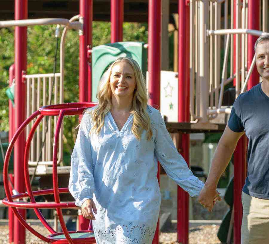 Two children running toward smiling parents at a community park. 