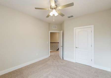 Carpeted bedroom with a ceiling fan and a large closet.