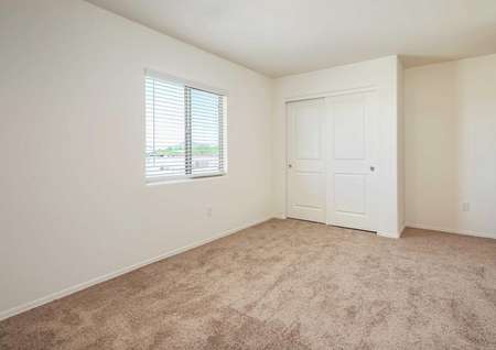 The Luna floorplan offers a second carpeted bedroom with a window with blinds.