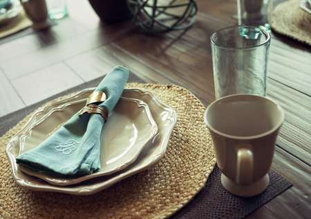 Dining table detail with coffee cup, plates and napkin.