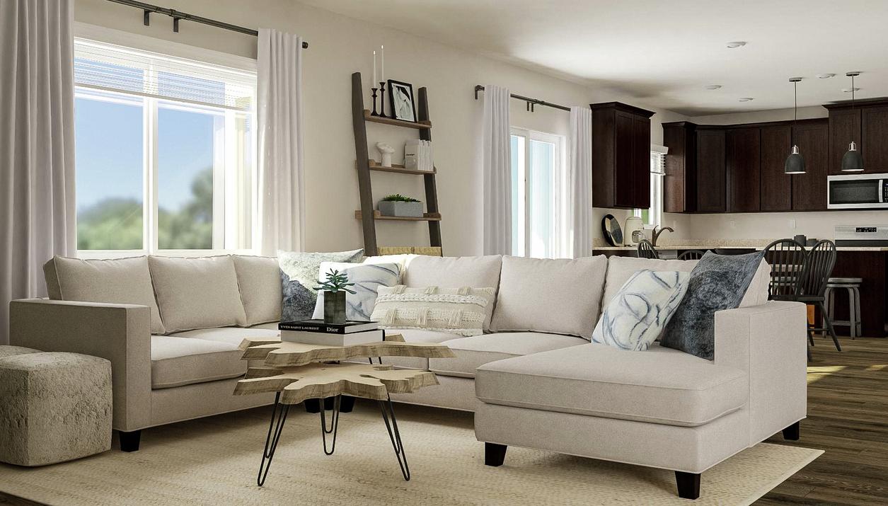 Rendering of the living room focused on a
  cream sectional couch and coffee table. The kitchen and stairway are visible
  in the background.