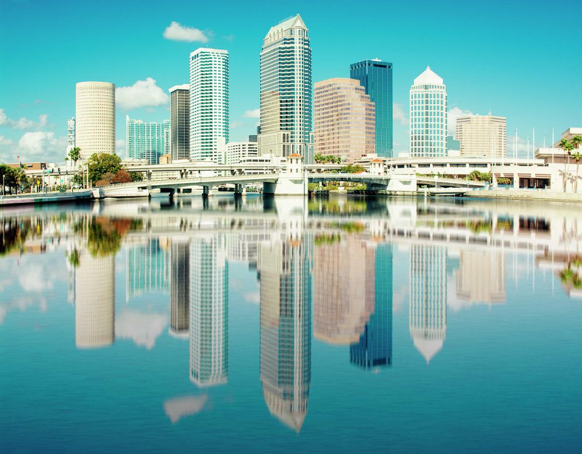 Tampa, Florida skyline with buildings reflecting into the water on a sunny, blue-sky day