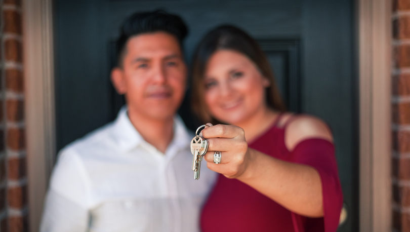 A smiling couple holding the keys to their brand-new home. 