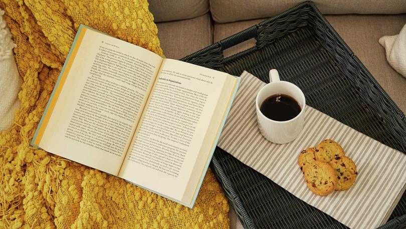 Trace home plan with open book, coffee mug, and cookies