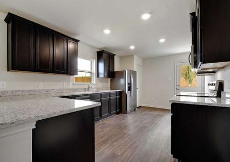 Medina kitchen with recessed lights, dark custom cabinetry, and light colored granite counters