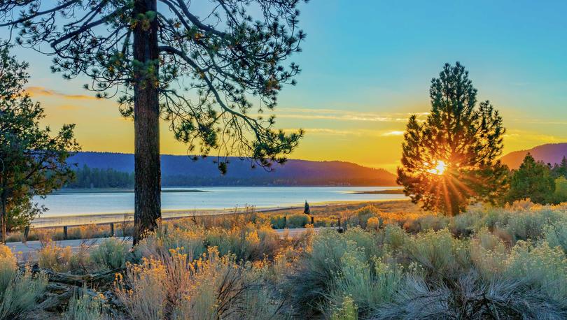 Riverside, California Big Bear Lake at sunset with pine trees, water, and mountains in the background
