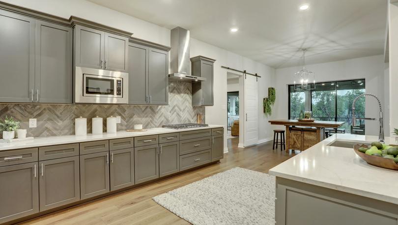Staged kitchen with gray cabinetry and white countertops.