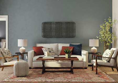 Rendering of living
  room with accent blue-gray wall and carpeted floor with rug, decorated with a
  cream couch, two accent chairs and coffee table.