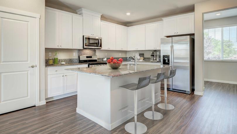 Fully furnished kitchen with white cabinets, granite countertops and breakfast bar in the Loomis floor plan.