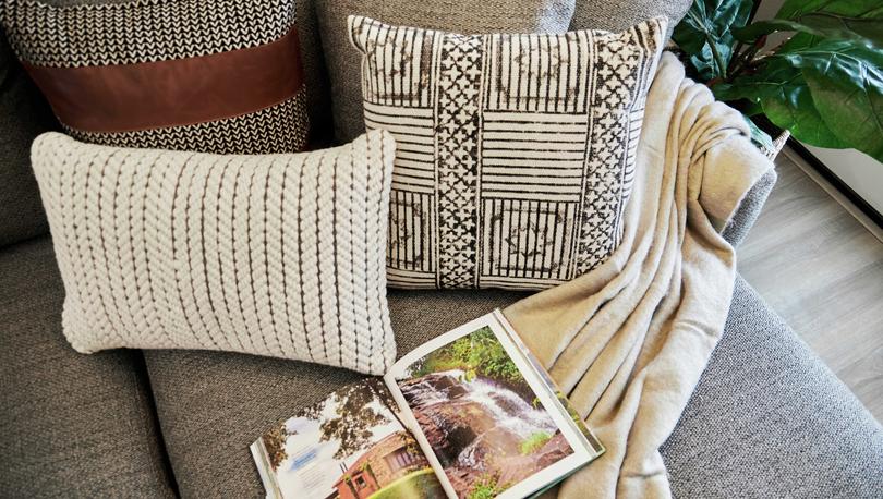 Staged couch with open book, pillows and blanket.