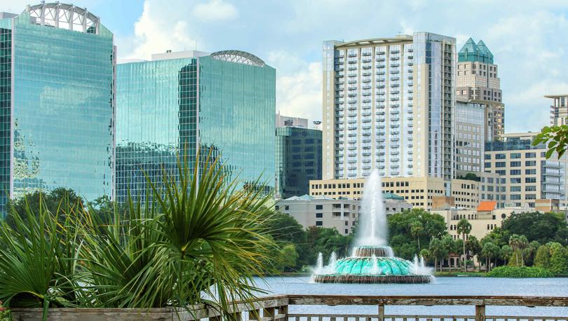 Orlando, Florida Lake Eola Fountain with glass-covered skyscrapers and blue skies in the background