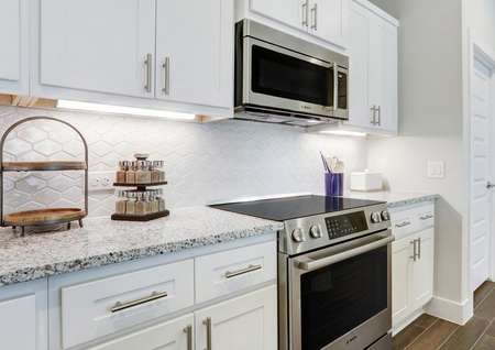 Staged kitchen with white cabinets, stainless appliances, and granite countertops. 