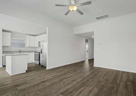 The spacious family room has plank flooring and a ceiling fan. 