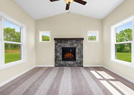 Photo of 4-season porch with carpet, a fireplace, ceiling fan and windows on all walls.