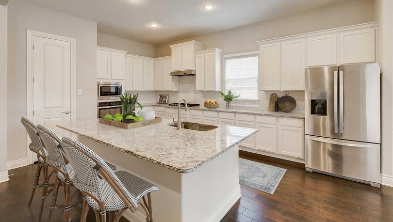 Staged kitchen with white cabinets with light granite and stainless appliances.
