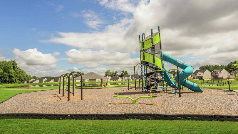 Side view of a play area with a playset, swings and a teeter toter in the community of Autumn Lakes.