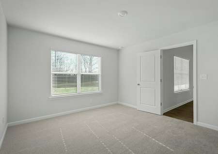 The master bedroom has a large window and carpet.