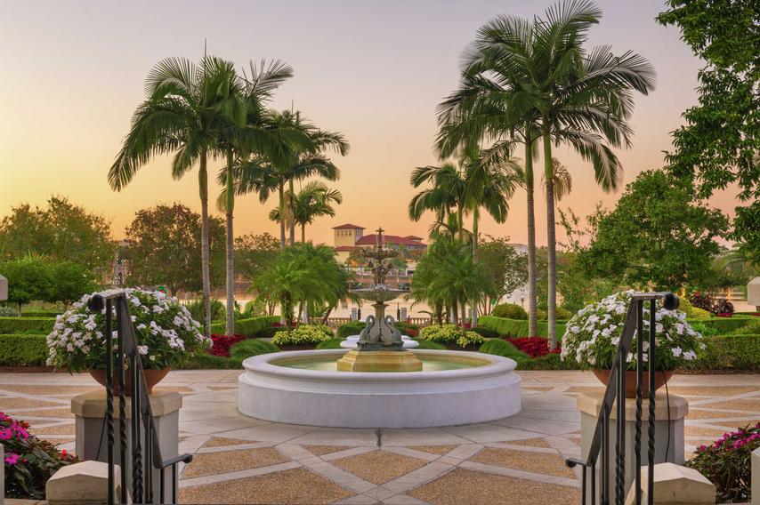 Lakeland, Florida gardens taken early evening showing a water fountain, palm trees, and red-roofed buildings in the distance