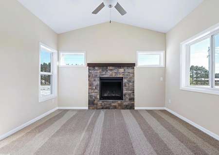 Photo of four-season porch with a fireplace, carpet, a ceiling fan and windows on all three walls.