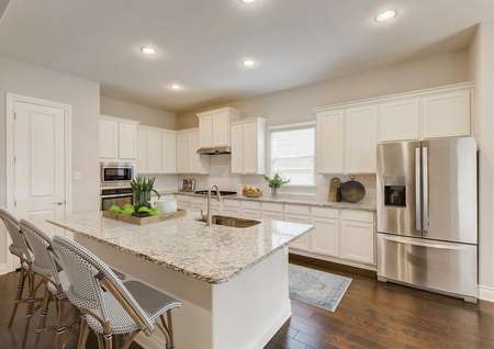 Staged kitchen with white cabinets with light granite and stainless appliances.