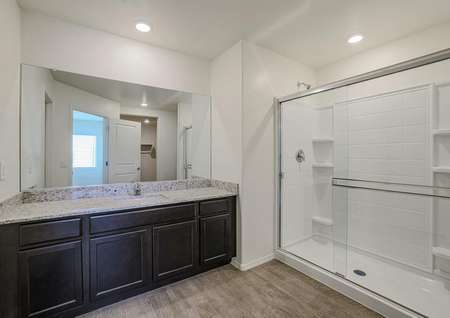 Master bathroom with granite countertops, espresso cabinets, and sparkling white shower with glass sliding doors.