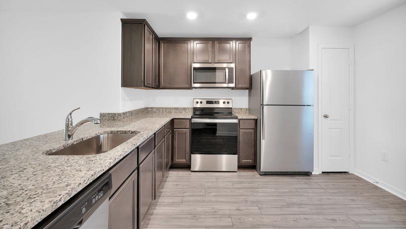 Full kitchen view showing appliances, cabinets and luxury vinyl plank flooring.