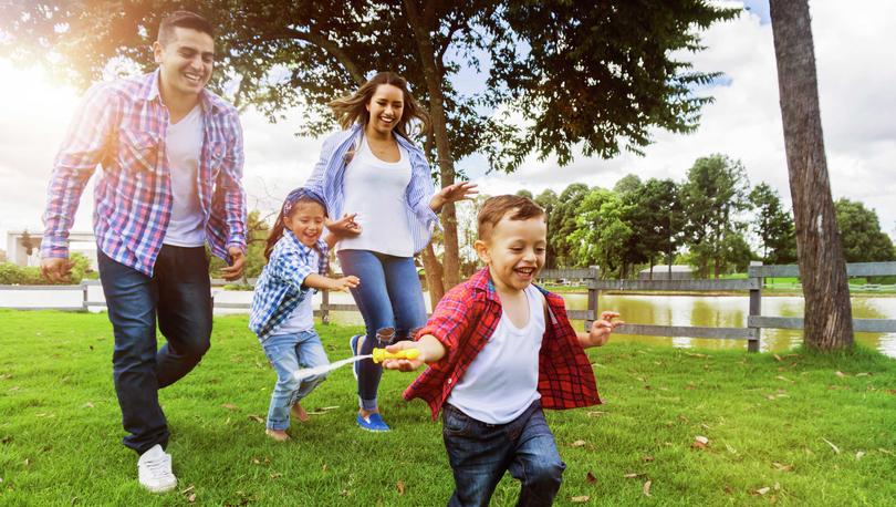 A family of four running near a pond.