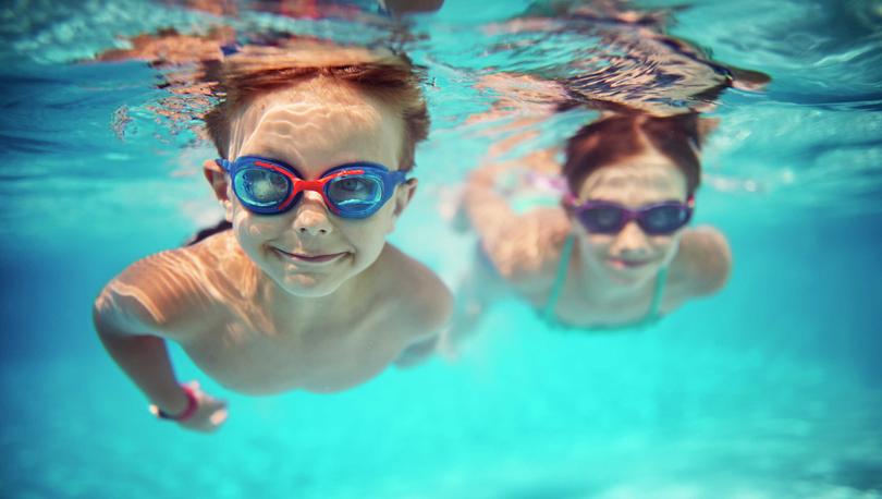 Two children swimming under water wearing goggles.