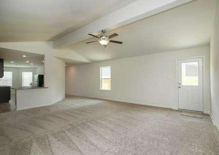 Pecos great room with carpeted floors, white back door with window, and access to kitchen