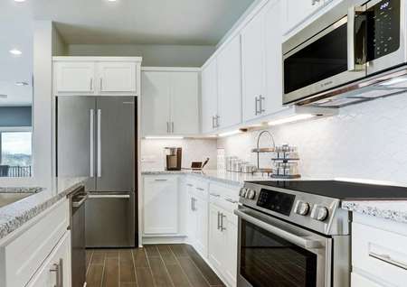 Staged kitchen with white cabinets, stainless appliances, and granite countertops. 