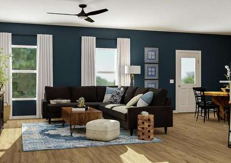 Rendering of the
  open floor plan showcasing the living room with ceiling fan and two windows,
  black couch and wood coffee table, with the dining room and kitchen visible
  in the back
