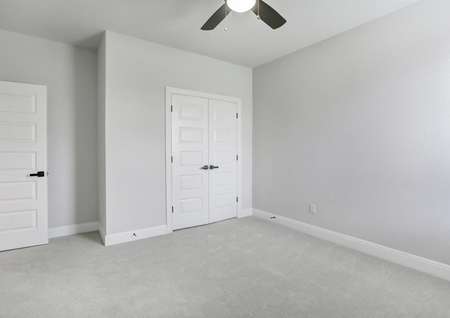 Guest bedroom with a ceiling fan, a closet with double doors, and light gray carpet.